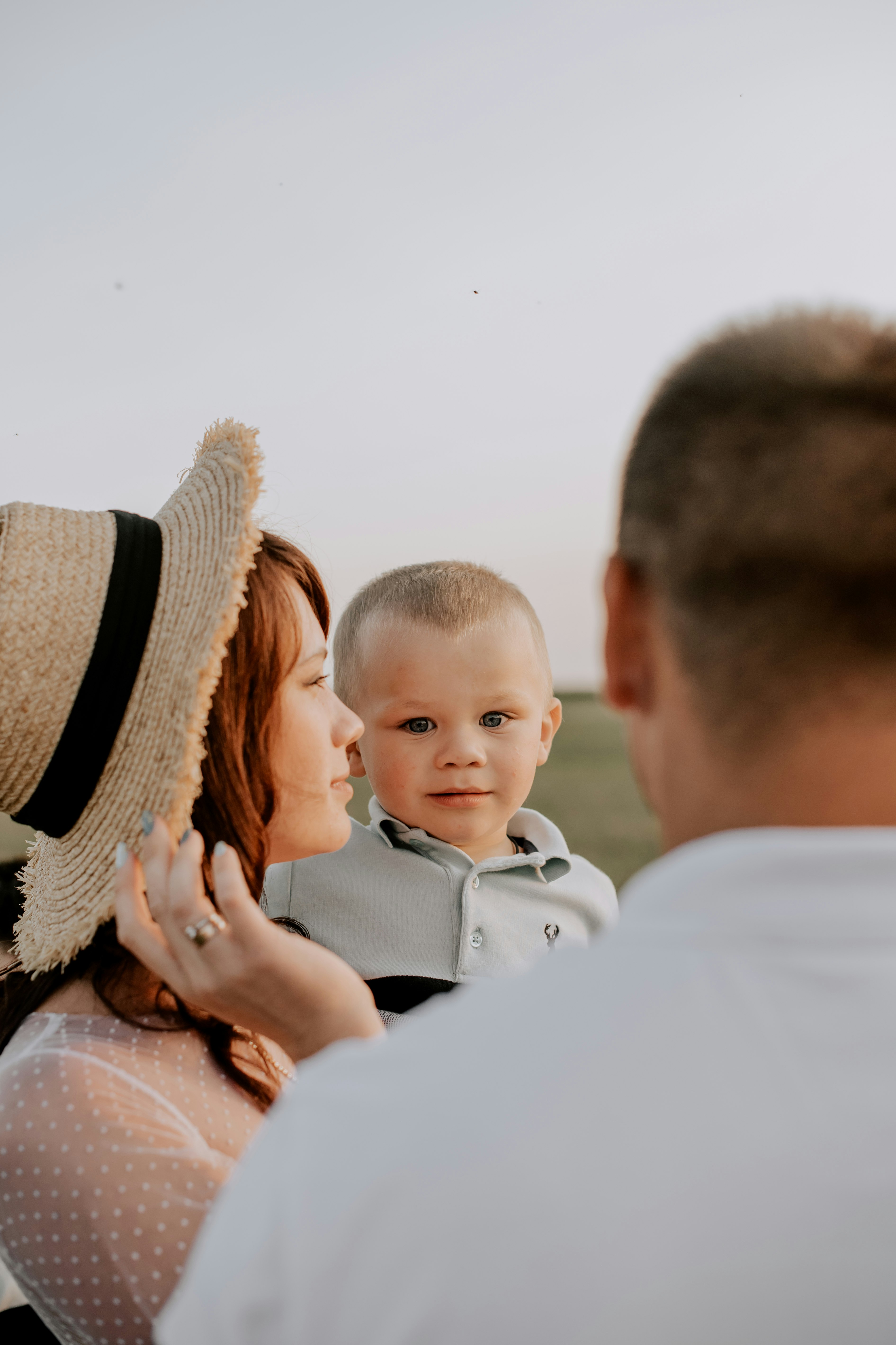 man in white shirt carrying baby in blue polo shirt